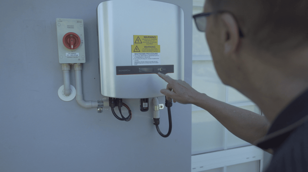Customer looks at solar inverter outside home and points at LED display
